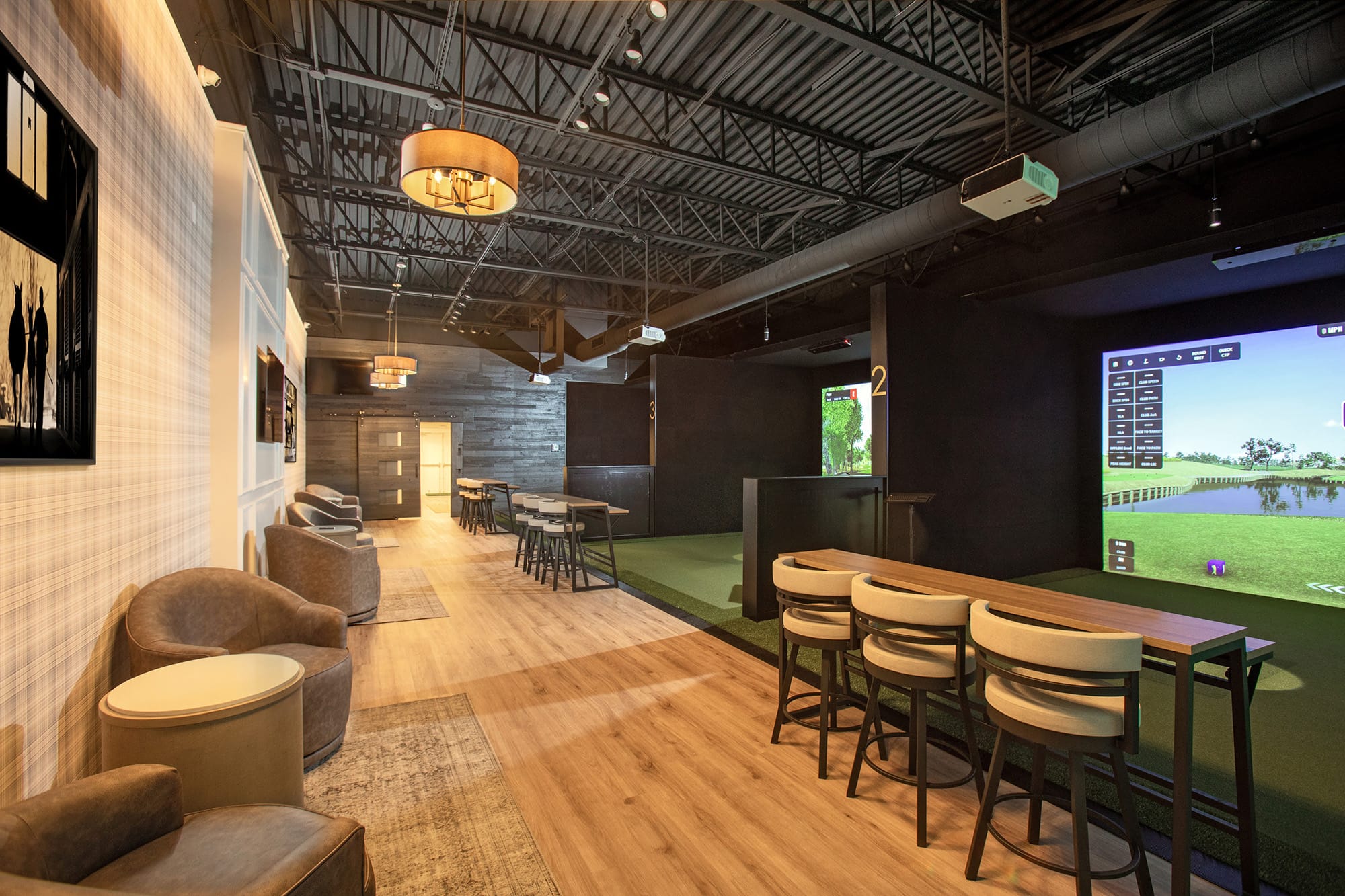 Modern golf simulator facility with multiple bays and warm sports bar atmosphere