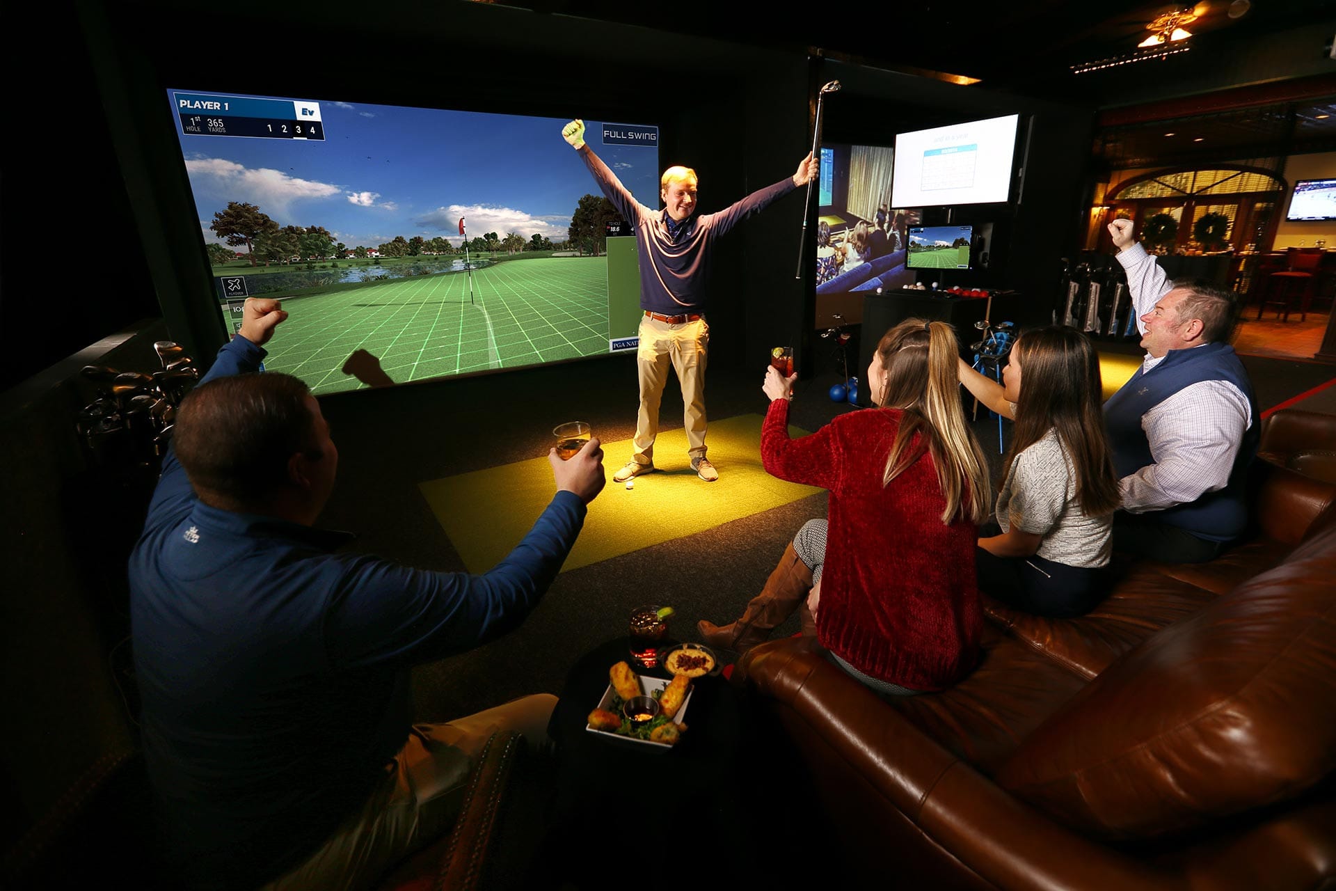 Group of friends celebrating in a golf simulator bay