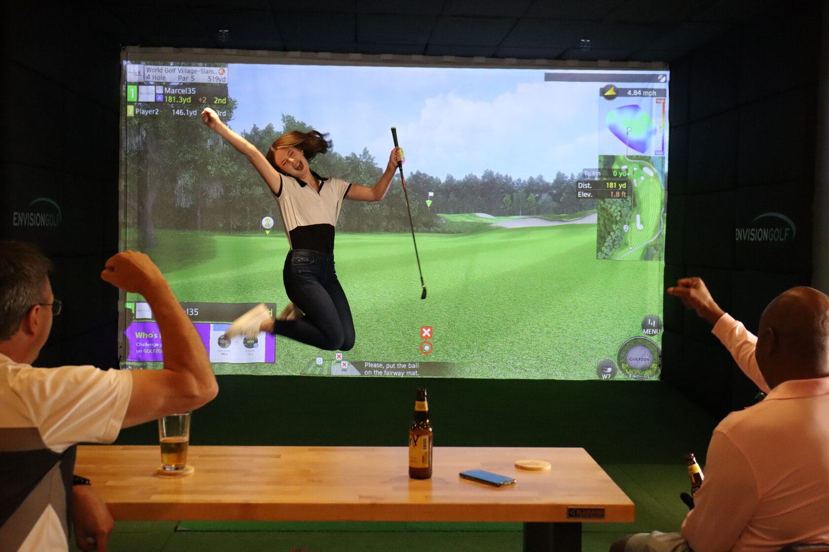 Friends celebrating a great shot in a golf simulator bay
